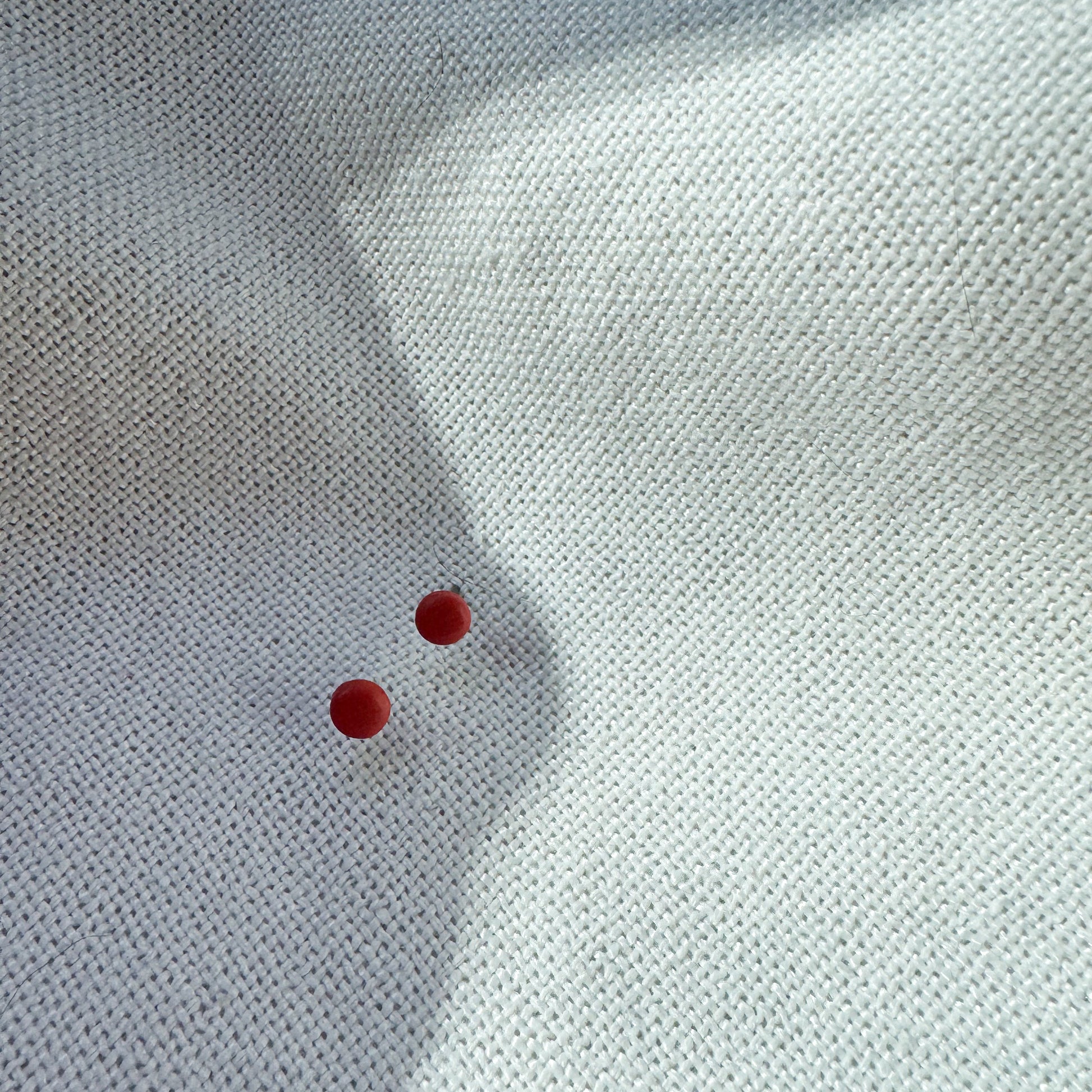 two small round rust-colored stud earrings against a white neutral background