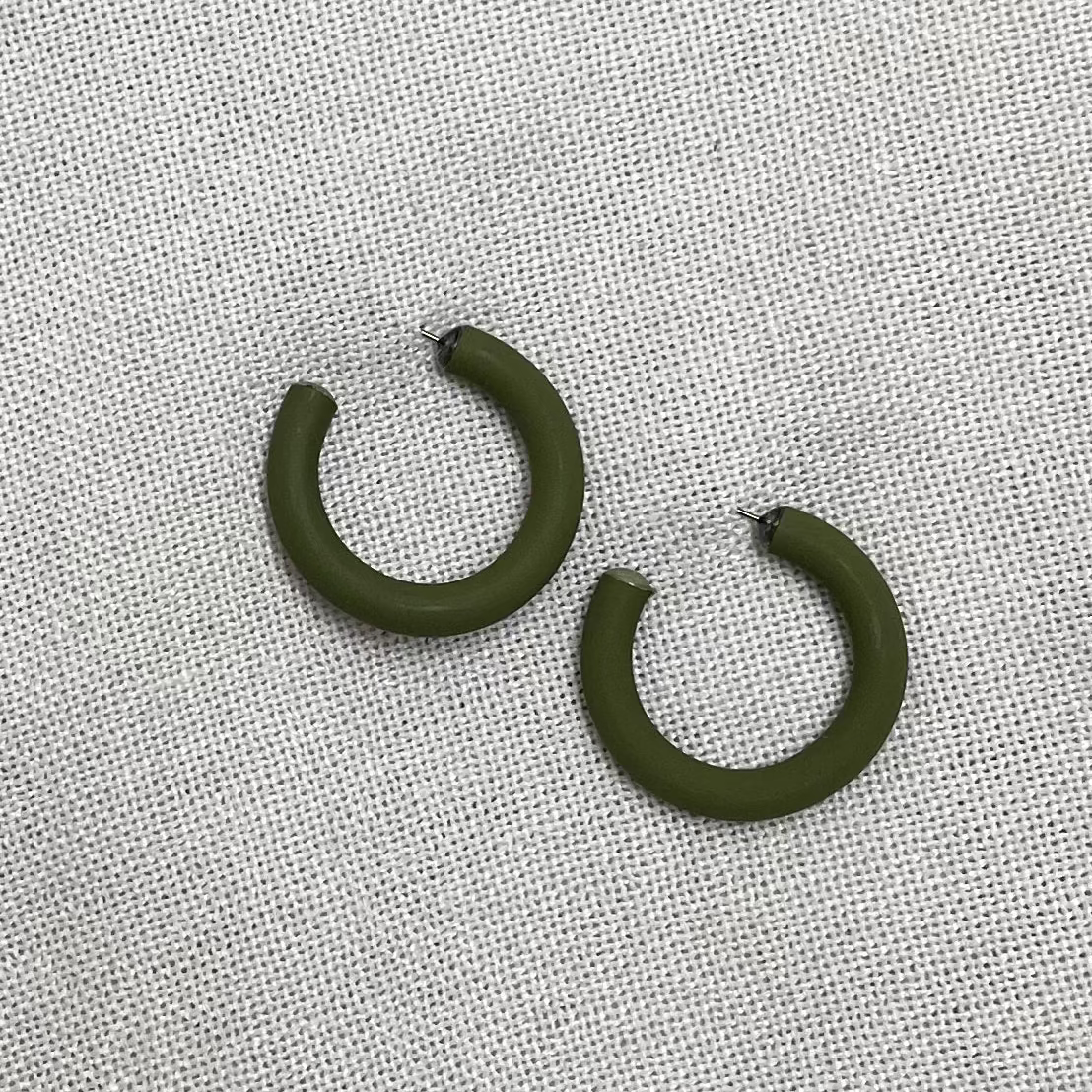 a pair of green clay earrings on a white fabric background
