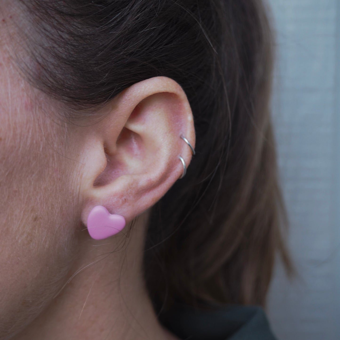 model wearing light pink clay stud earrings that are heart-shaped