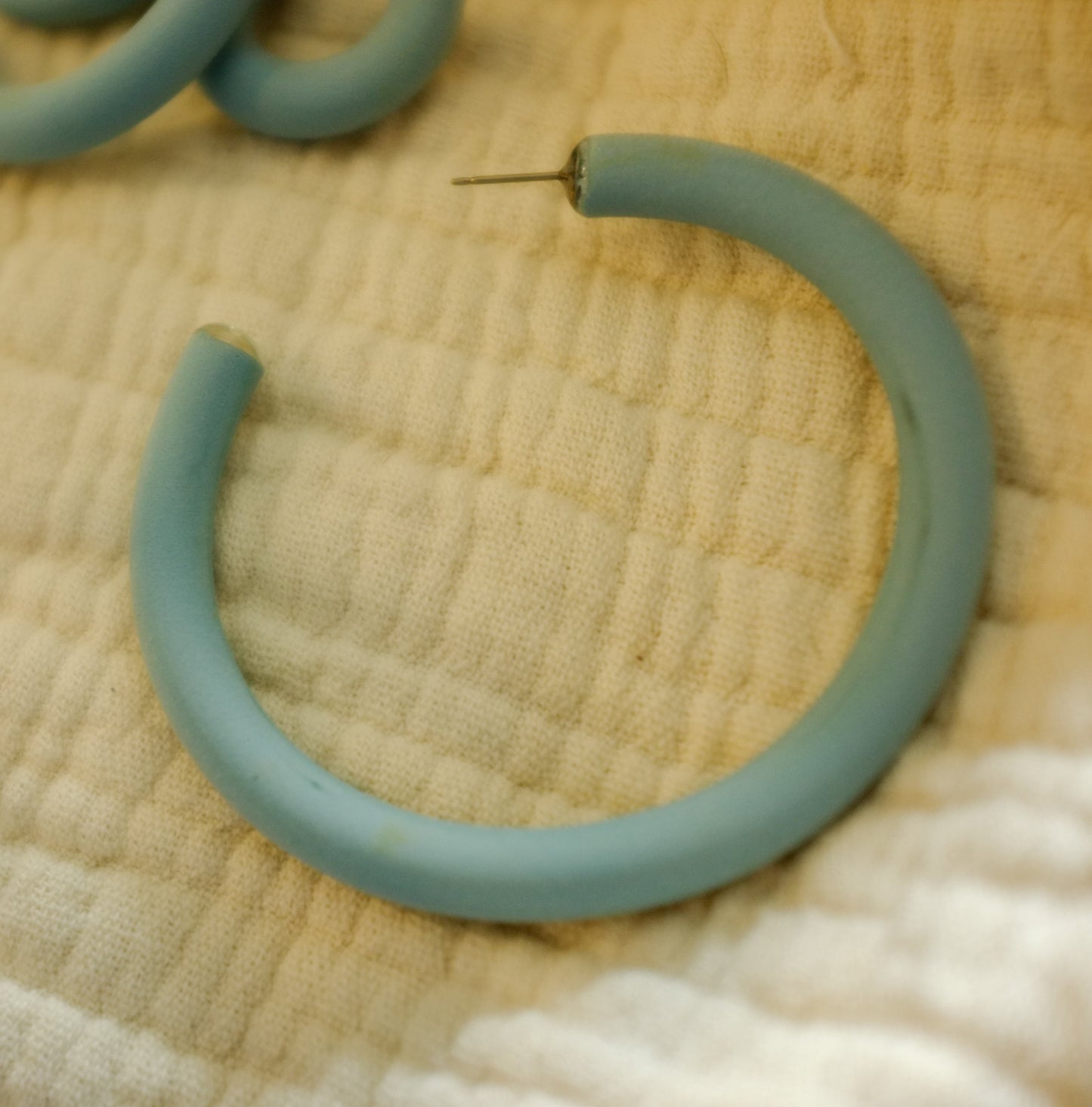 light blue hoop earrings with post studs on a textured fabric background