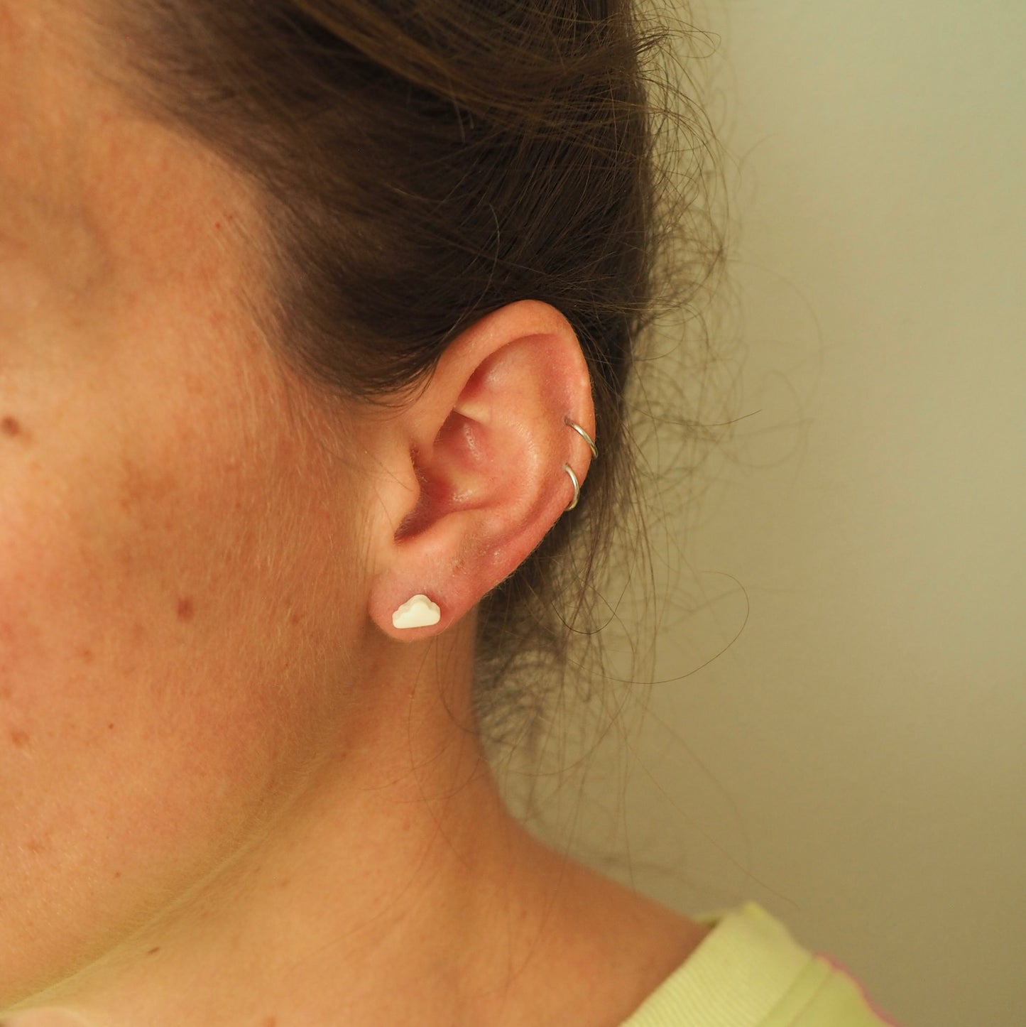 Model wearing small white cloud polymer clay stud.