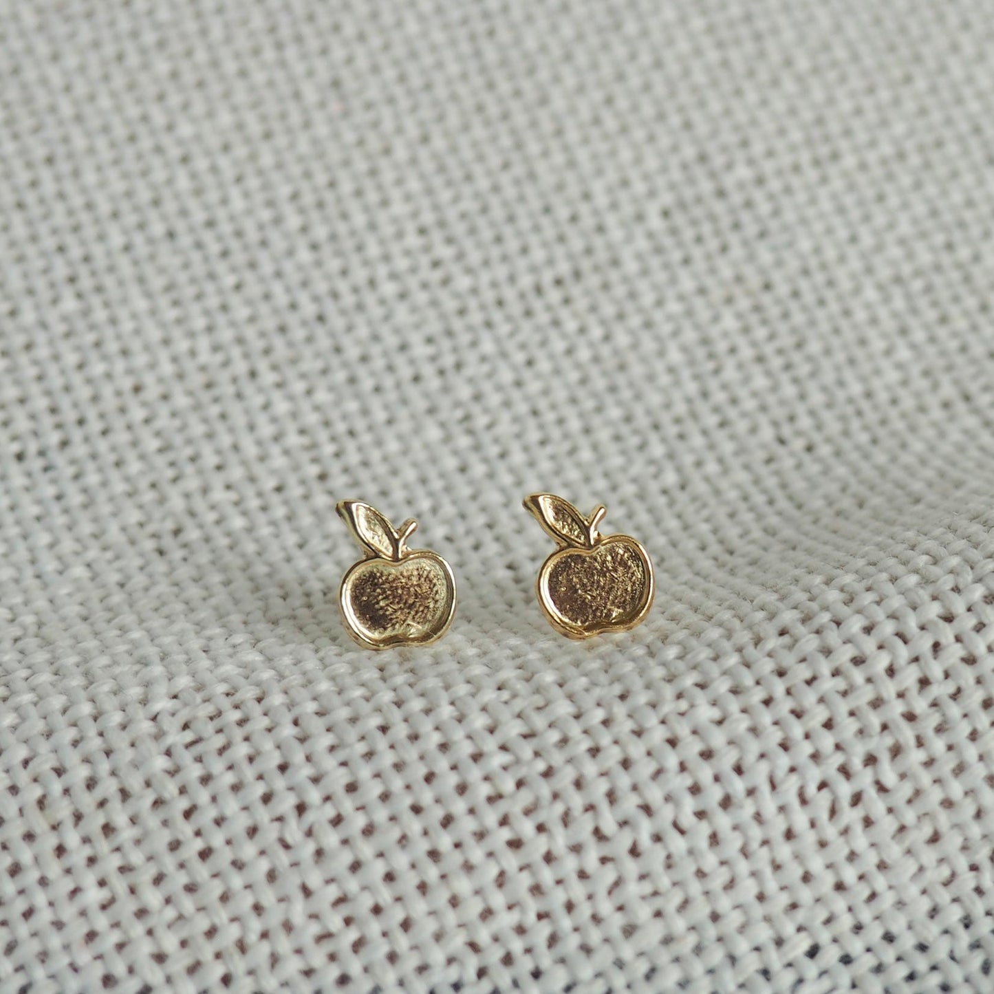 two small apple gold filled studs on a white neutral background 