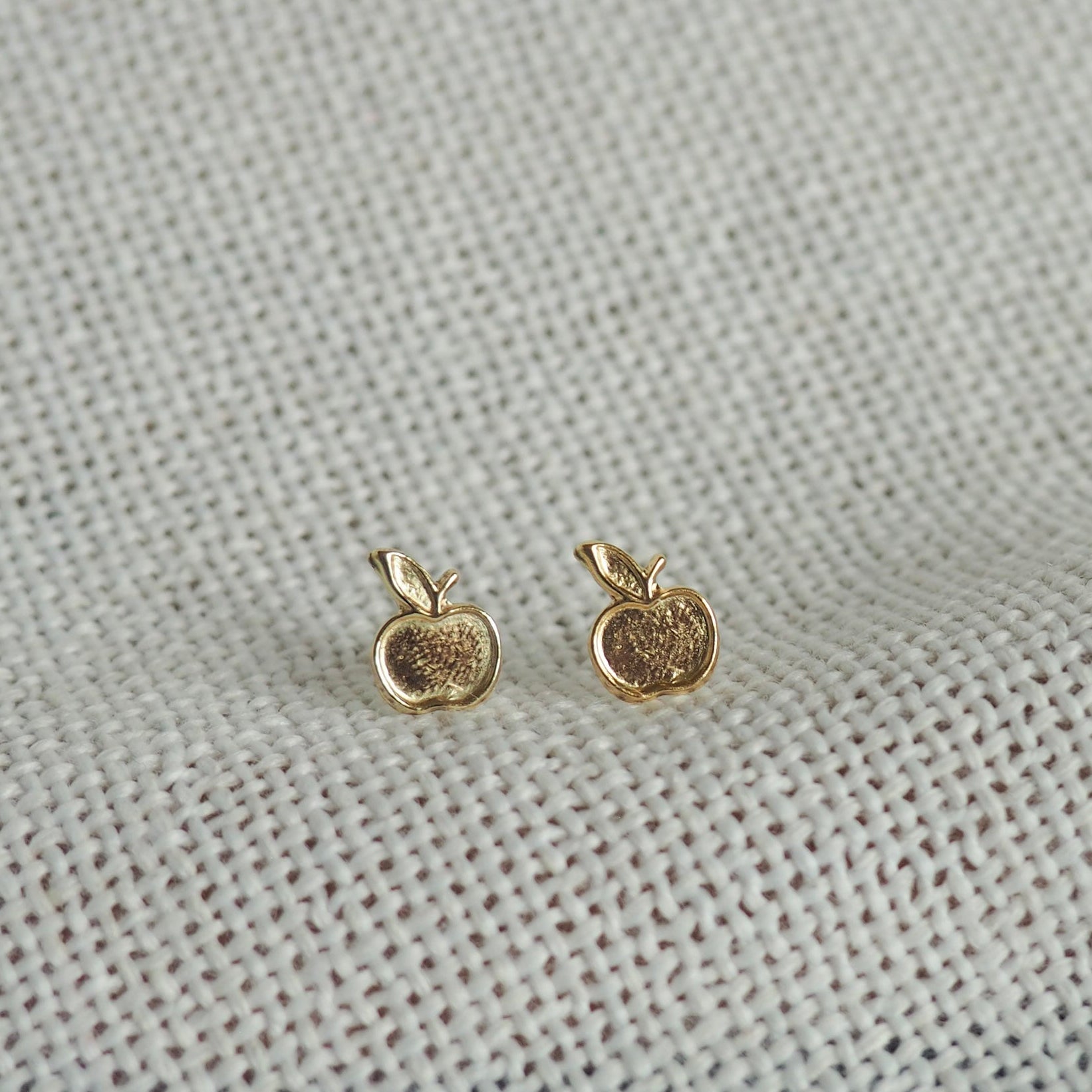two small apple gold filled studs on a white neutral background 