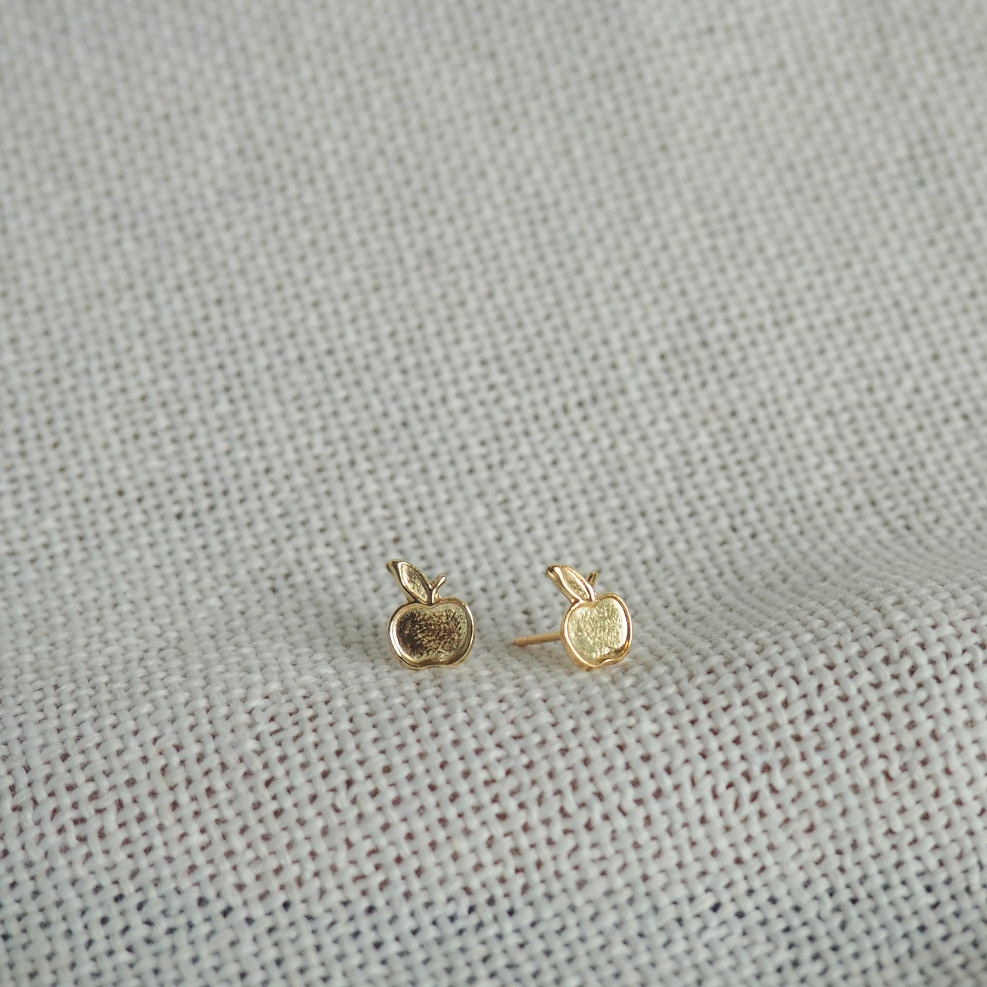 two small apple gold filled studs on a white neutral background 