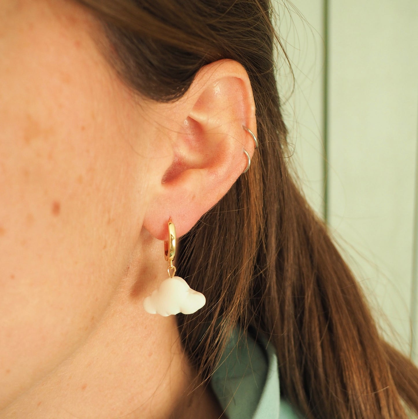 Model wearing white cloud polymer clay earrings with gold huggies 