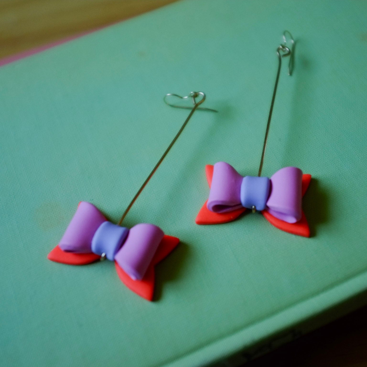 Colorful bow-shaped earrings on a green surface