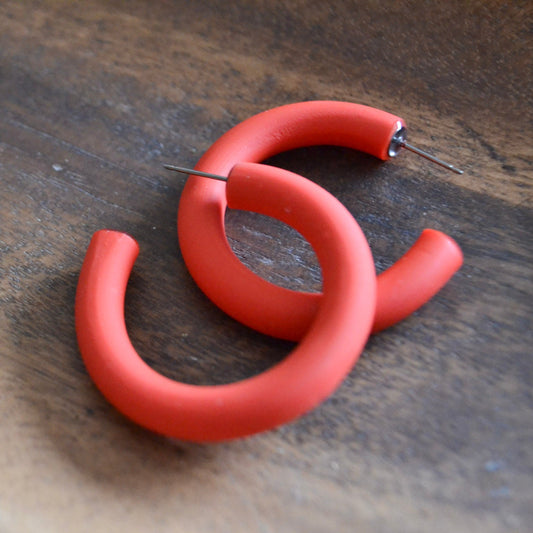 Pair of red hoop earrings on a wooden surface
