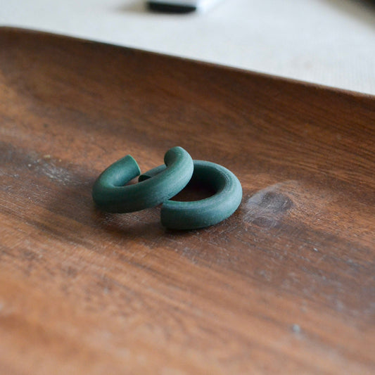 a pair of green clay earrings on a wood surface