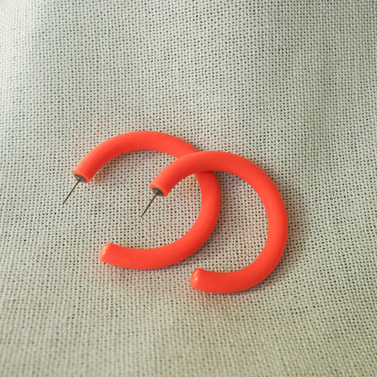 large coral hoop earrings white textured fabric background