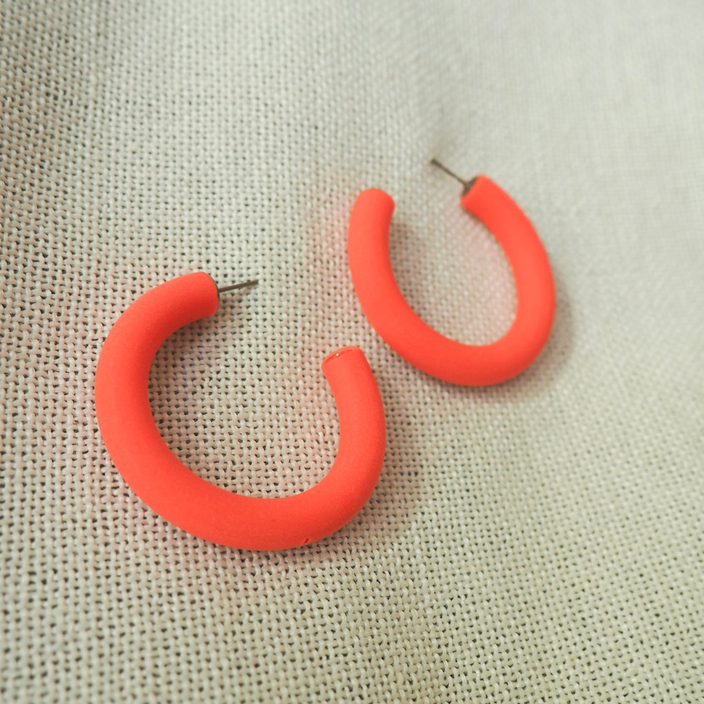 mid size coral hoop earrings white textured fabric background