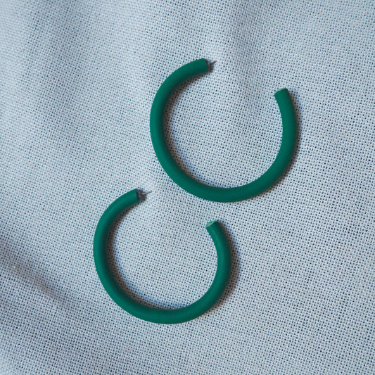 Large emerald green hoops on white textured background