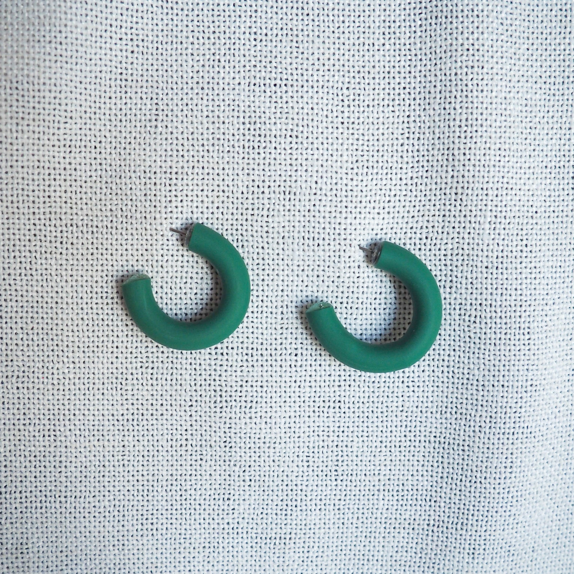 small emerald green hoops on white textured background 