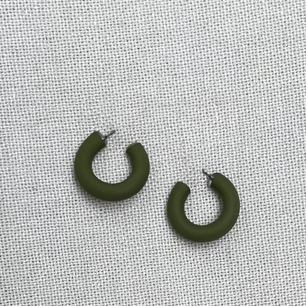 a pair of green clay earrings on a white fabric background