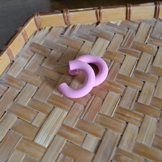 small light pink hoop earrings with post studs on a woven background