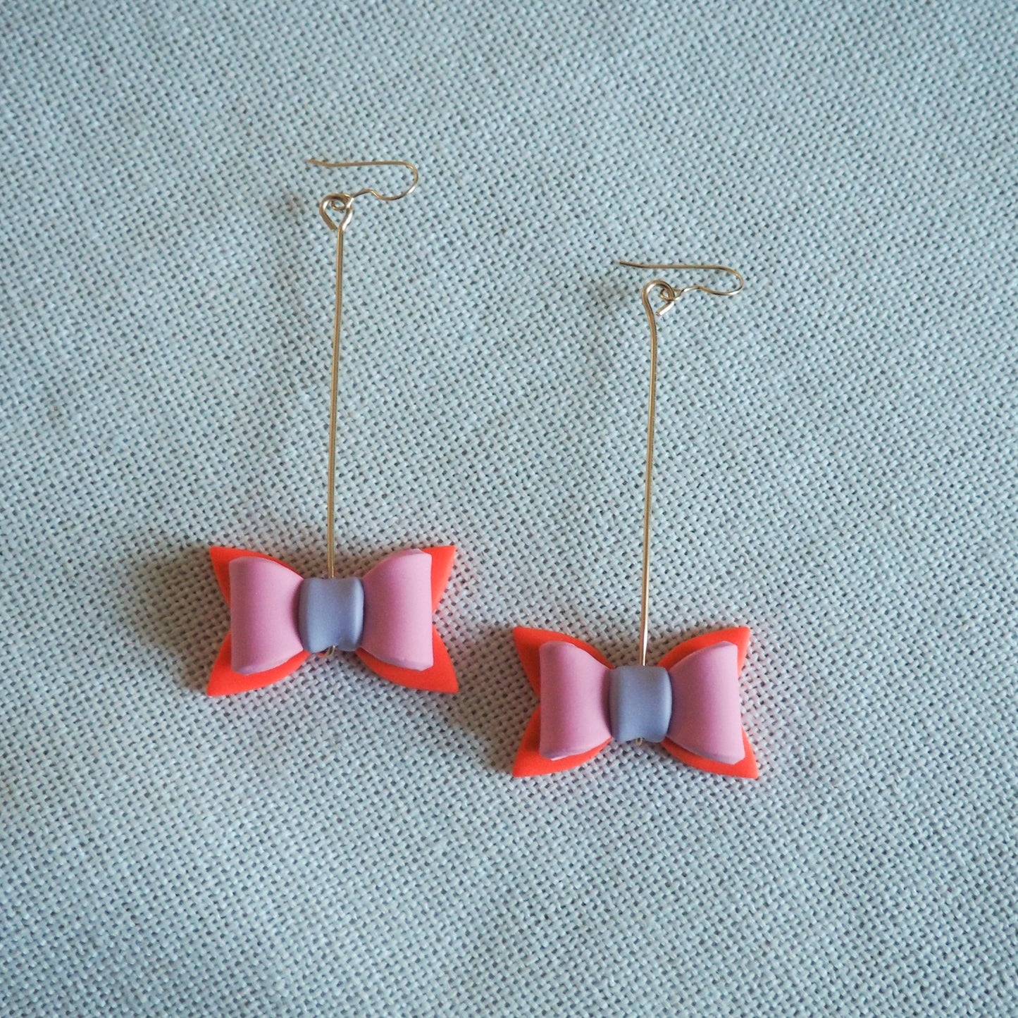 multicolored bow shaped earrings hung on gold pins with gold fish hooks 