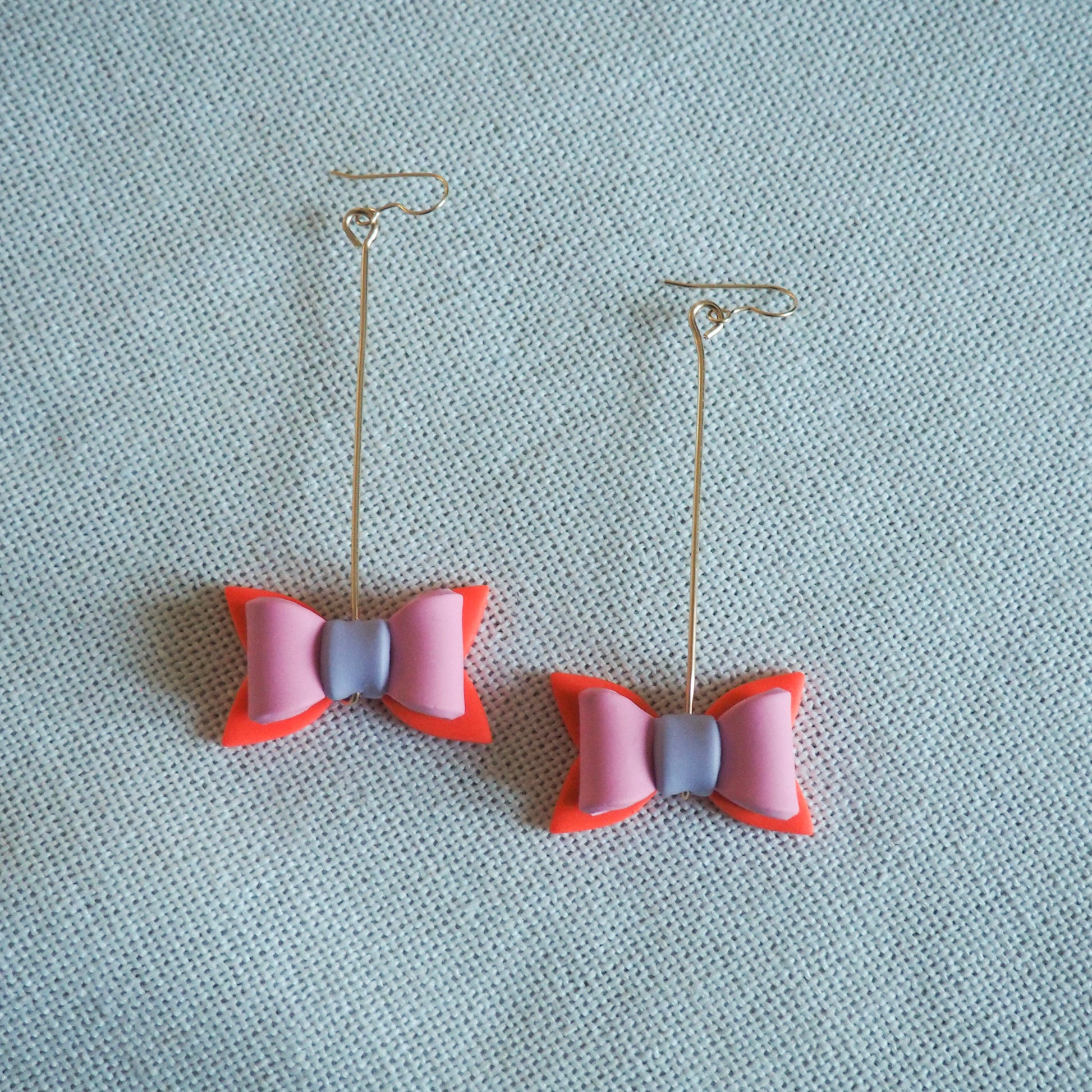 multicolored bow shaped earrings hung on gold pins with gold fish hooks 