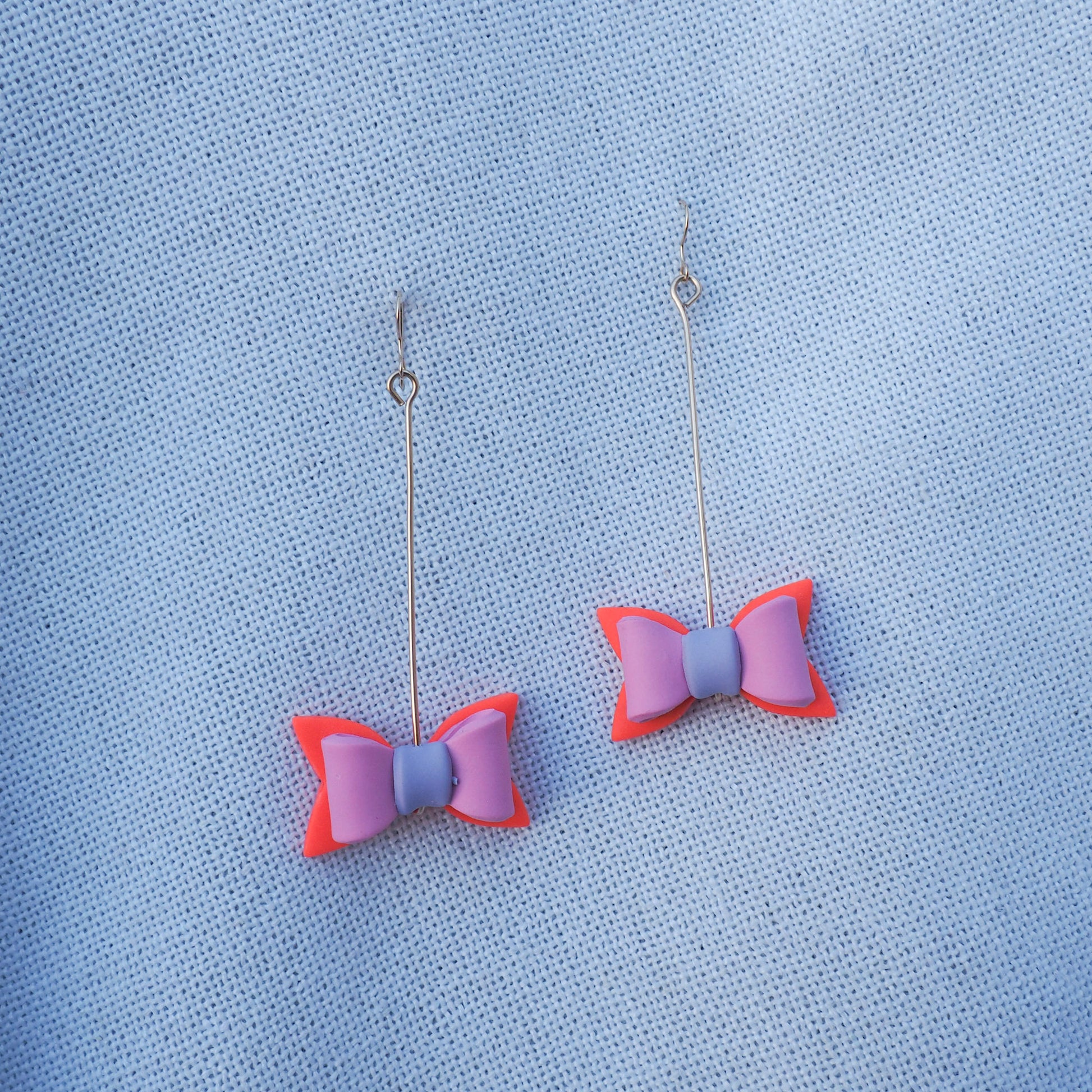 multicolored bow shaped earrings hung on gold pins with gold fish hooks 