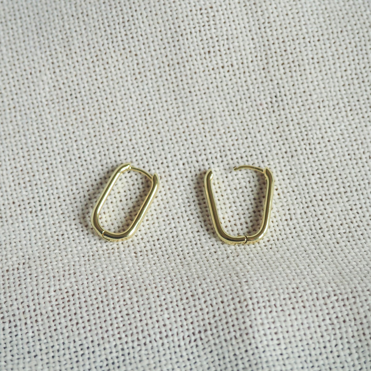 two oblong gold filled hoops- one hoop open and one closed - on a white neutral background