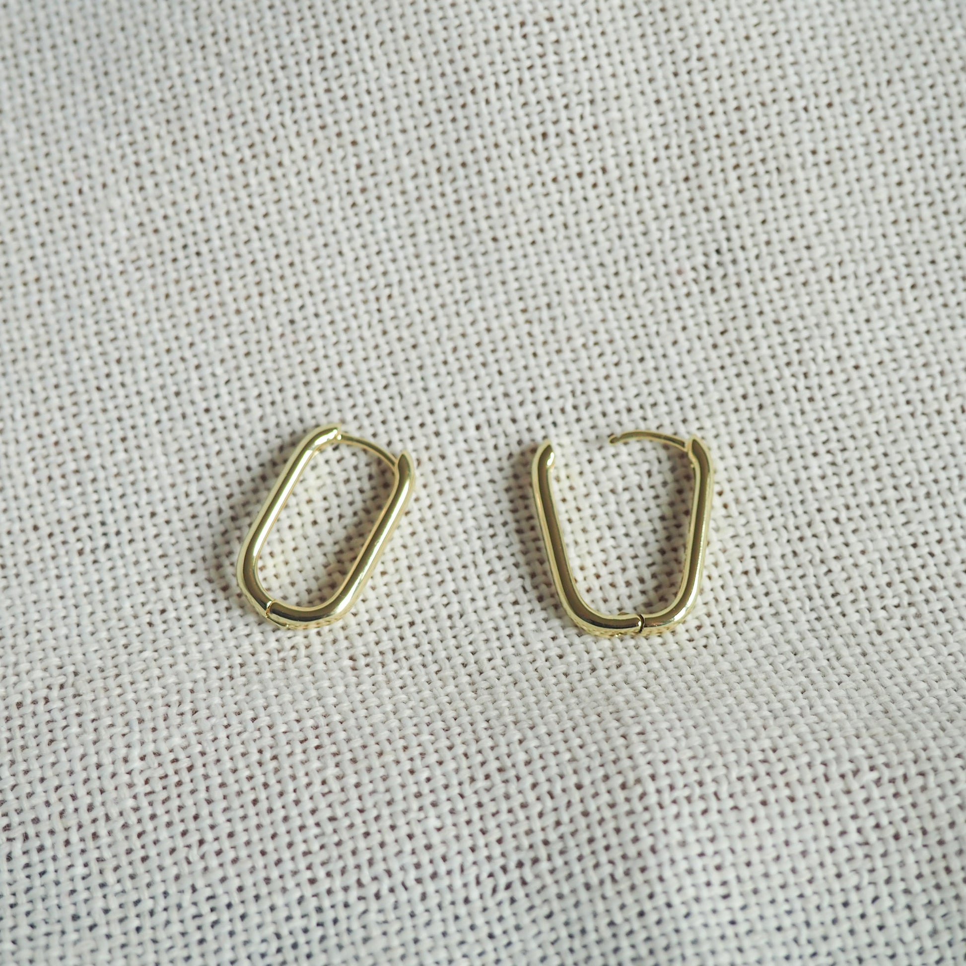 two oblong gold filled hoops- one hoop open and one closed - on a white neutral background