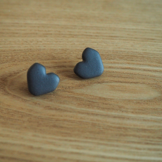 Black geometric heart polymer clay studs set on wood backdrop 