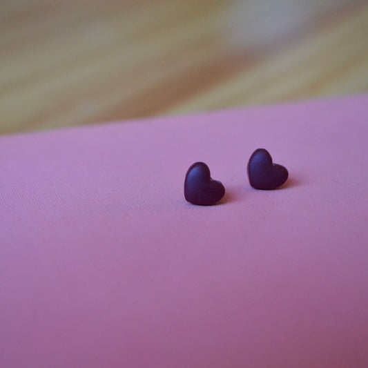 Small cranberry heart polymer clay stud earrings on light pink backdrop 