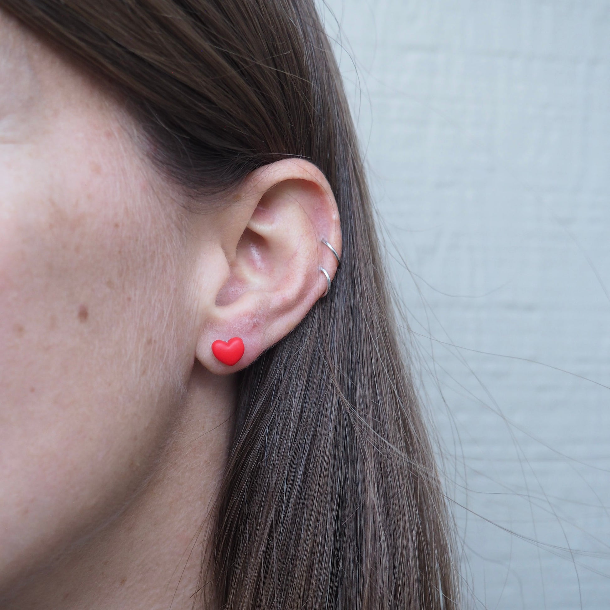 model wearing small red heart polymer clay stud earrings