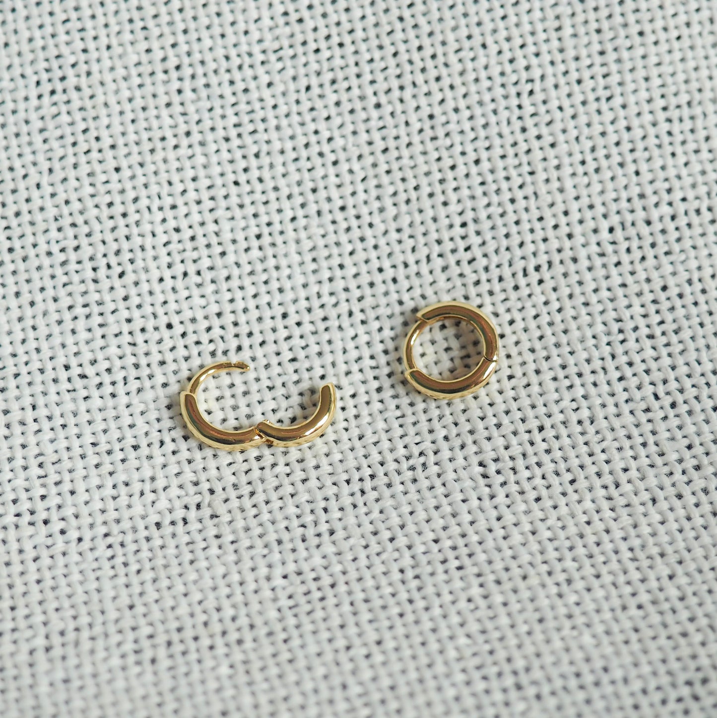 two small gold filled hoops- one open and one closed- on a white neutral background