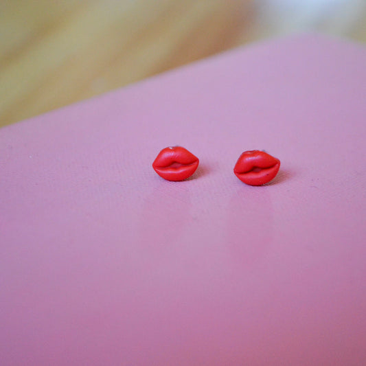 clay lip shaped stud earrings with titanium posts and backs on a pink backdrop