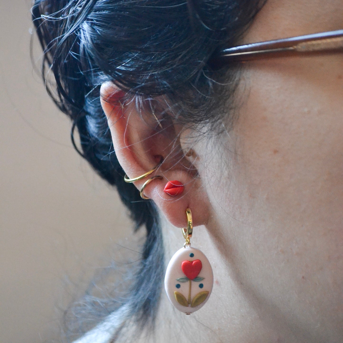 model wearing clay lip shaped stud earrings  with titanium posts and backs and other earrings 