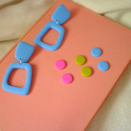 Blue earrings with colorful circle studs on a pink card