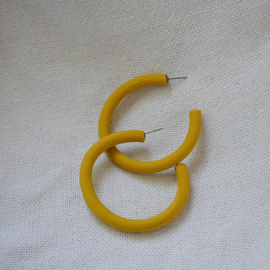 Yellow hoop earrings on a light gray fabric background