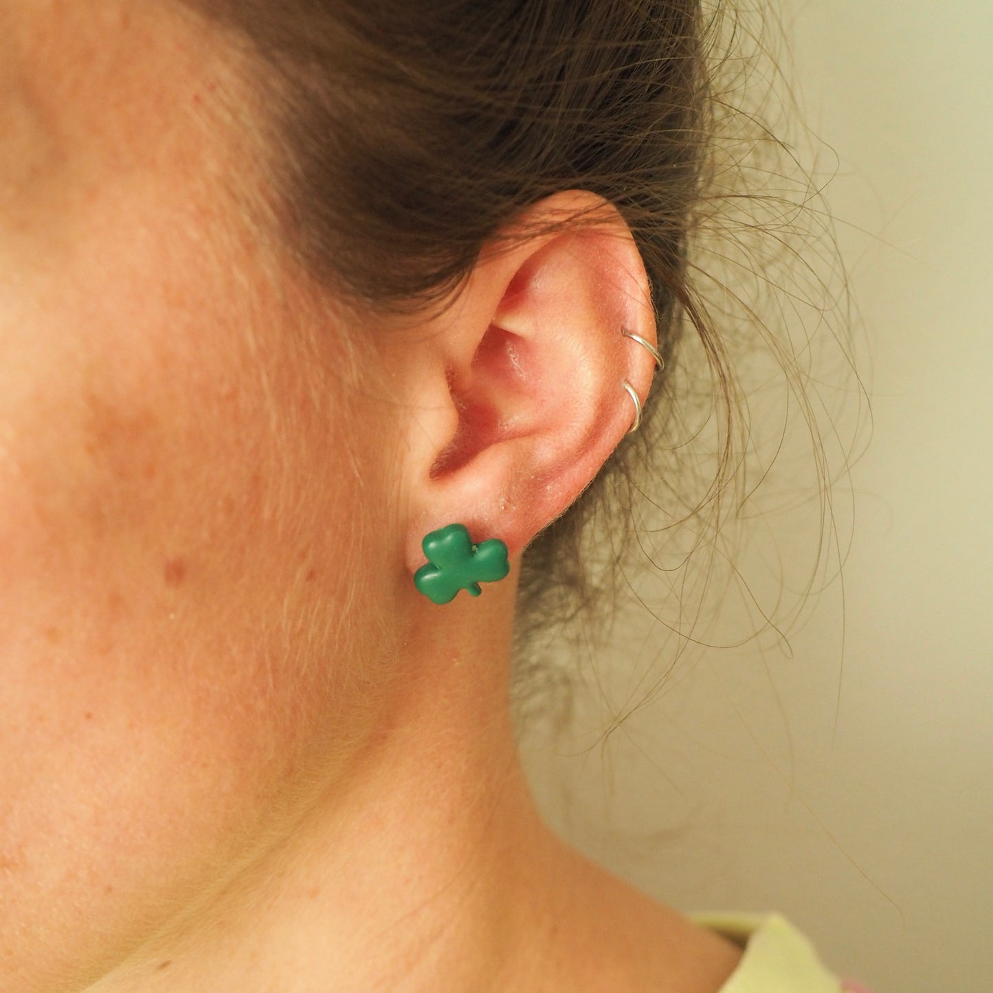 Model wearing small green shamrock polymer clay stud. 